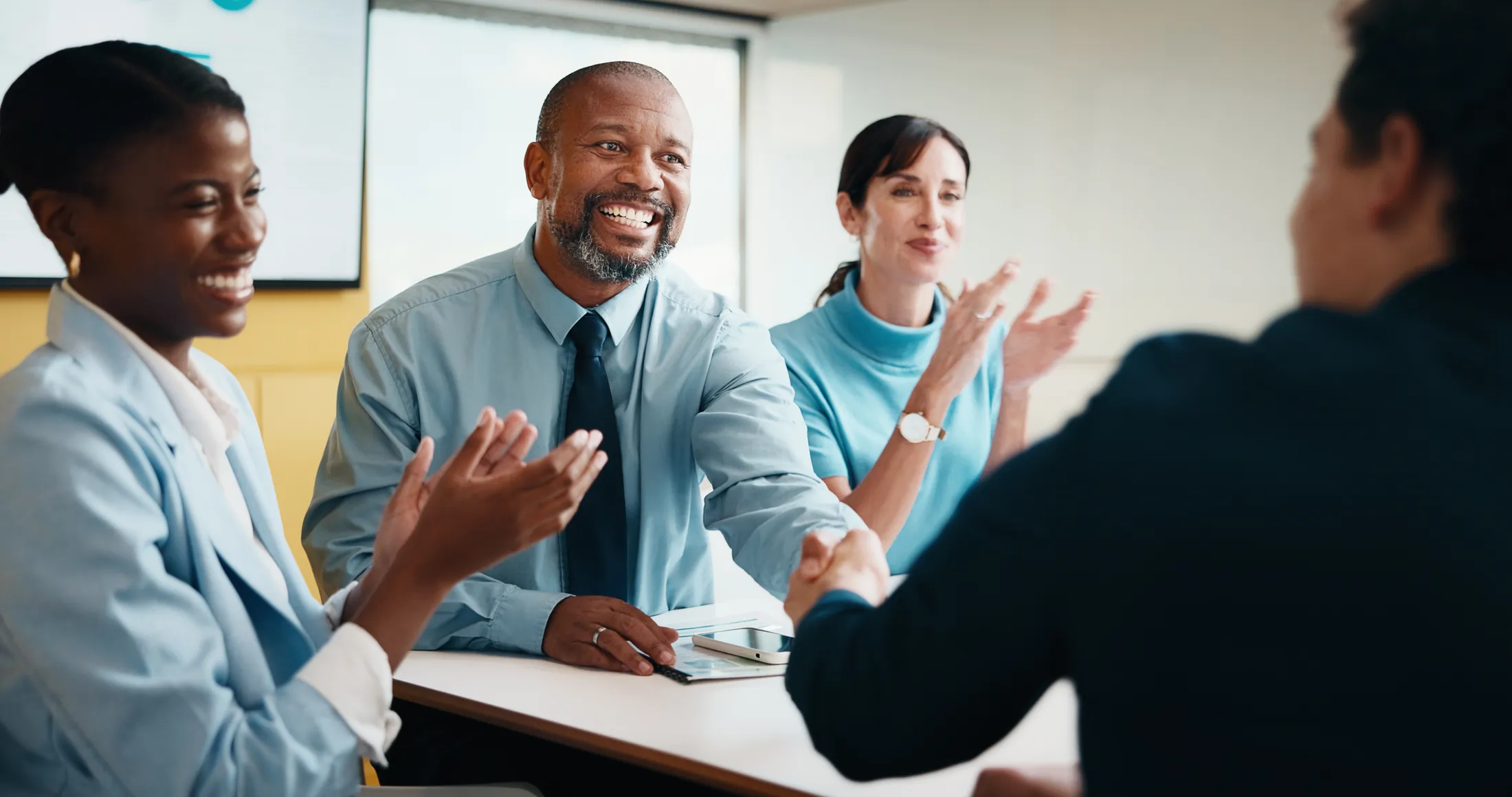 Colleagues applauding and shaking hands at the end of a meeting